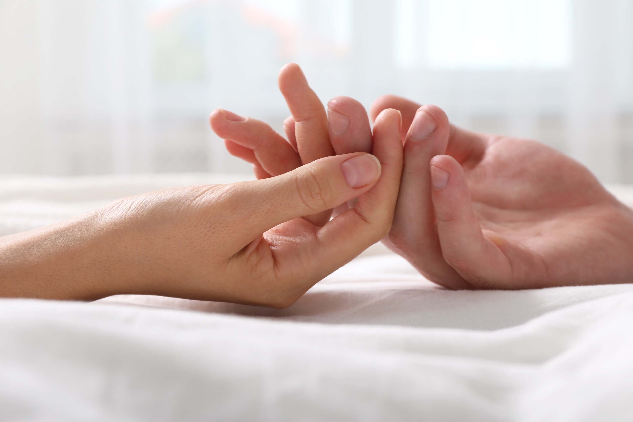 A close-up of a hand holding a person's hand

Description automatically generated